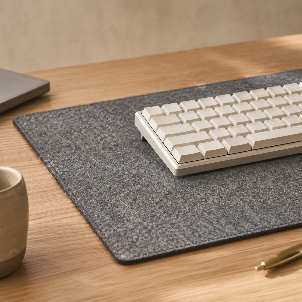 Grovemade wool felt desk pad in oatmeal with visible stitched edges and woven texture on a light oak desk