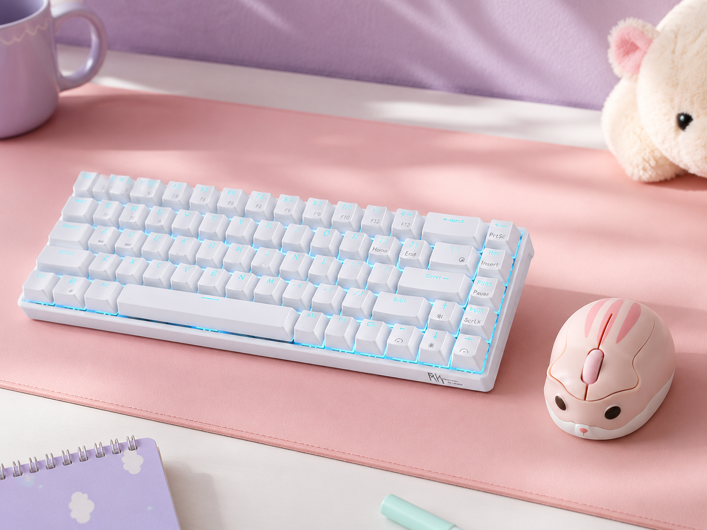 A pastel pink mechanical keyboard and hamster-shaped wireless mouse on a pastel desk mat in a kawaii workspace