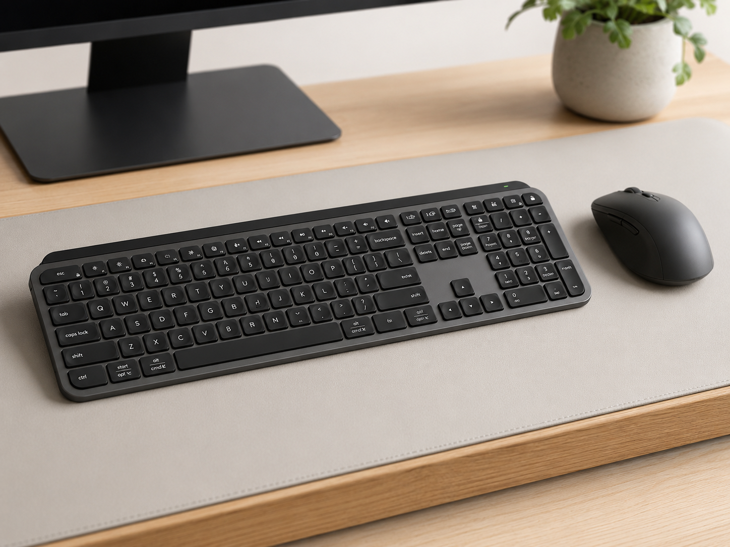 A clean low-profile keyboard and minimalist wireless mouse in monochrome tones on a neutral desk mat